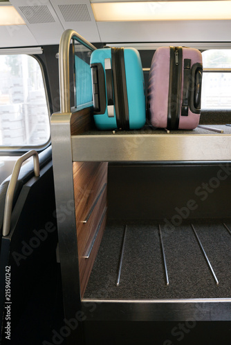 Bright blue and purple suitcases on a luggage rack inside a train carriage
