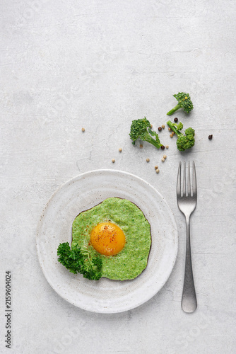 Fried egg with green broccoli puree on a plate, healthy keto diet breakfast