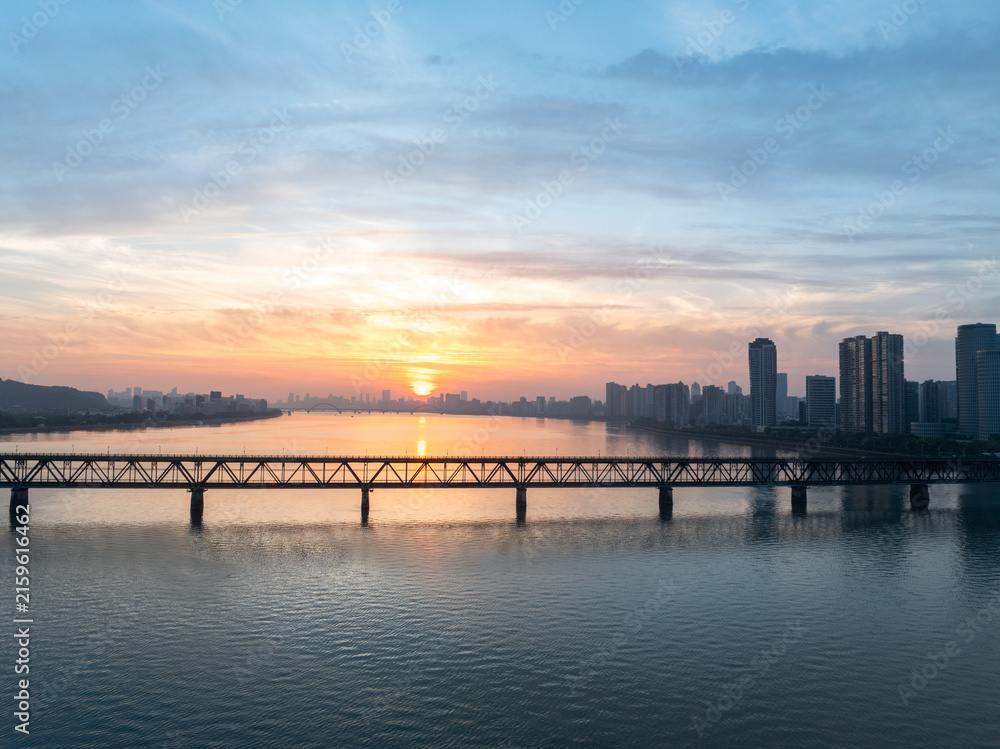 Fototapeta premium sunset view of a large bridge spanning the river with city skyline