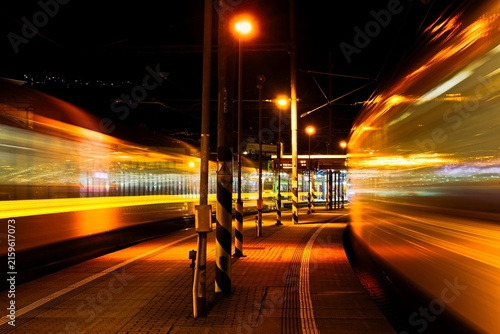 light lines of a passing train at night railway station