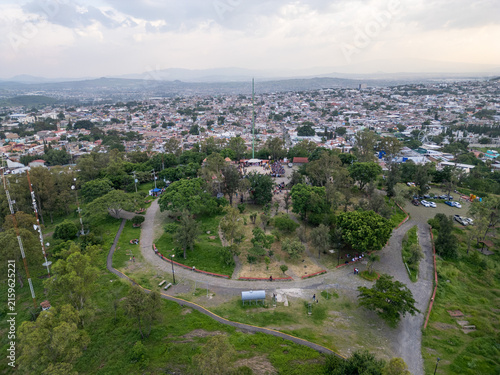 Captivating aerial drone perspective of Queen's Hill in Tonala, Jalisco, revealing a vast cityscape and natural park. The scenic viewpoint offers panoramic vistas of the surrounding urban landscape.