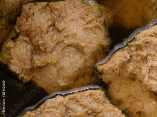 Raw soy cutlets soaking in aromatic vegetable broth, placed in a black bowl and ready for breading. Fresh chicken eggs and fine breadcrumbs on parchment paper are visible nearby. Ingredients for a veg