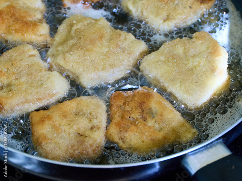 Golden brown breaded soy cutlets frying in hot, bubbling vegetable oil in a pan. Close-up view of traditional vegetarian schnitzels cooking until crispy.