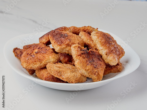 Fried, golden-brown soy cutlets served on a white plate with a fork. One of the cutlets is sliced ​​open, revealing the fibrous texture of the vegan meat substitute. A bright, high-key food photograph