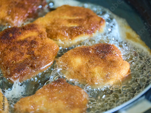Golden brown breaded soy cutlets frying in hot, bubbling vegetable oil in a pan. Close-up view of traditional vegetarian schnitzels cooking until crispy.