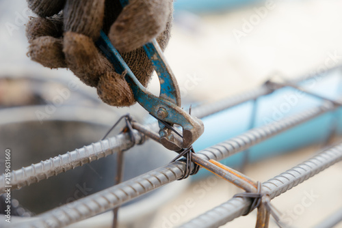 Принти на полотні A close-up image of construction workers tying reinforcing steel bars with wire using hand-crank reinforcing steel pliers before pouring concrete