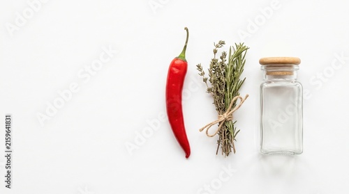 Fresh Red Chili Pepper and Green Herb Bundle with Glass Jar on White Background