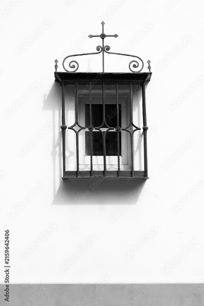 Obraz premium Window with wrought iron lattice on whitewashed facade in Seville city