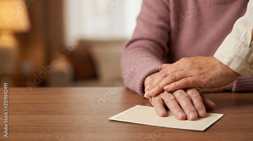 Caregiver or relative holding hands of senior woman on old photograph at home, family support empathy and comfort for elderly patient with dementia memory loss website banner