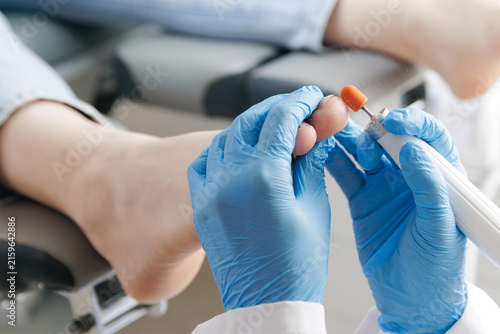 Foto Caucasian female podiatrist treating adult patient feet in clinic setting, toena