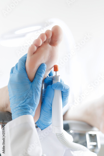 Принти на полотні Podiatrist performing foot treatment on patient with medical tool