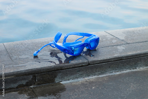 Bild auf Leinwand Blue diving mask rests on wet stone edge