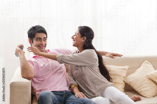Playful young man keeping remote control away from woman 