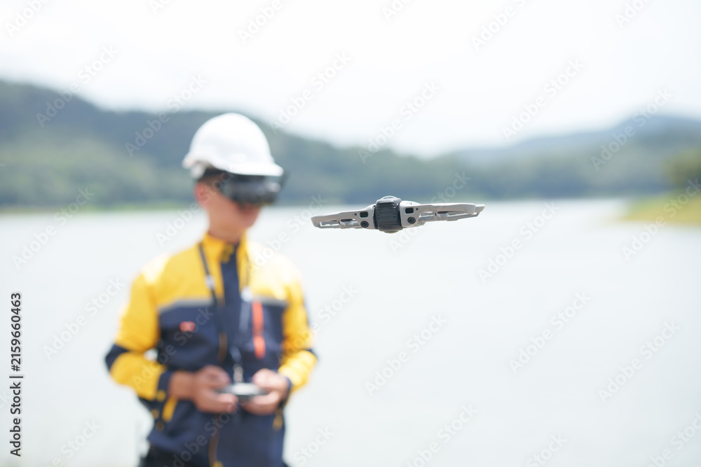 Naklejka premium Engineer Operating Drone with FPV Goggles near Lake
