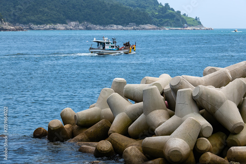 Small Commercial Fishing Boat Navigating Behind Coastal Tetrapod Jetty