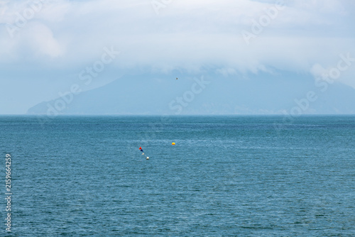 Calm Blue Sea Horizon with Low Clouds Blanketing Distant Mountain
