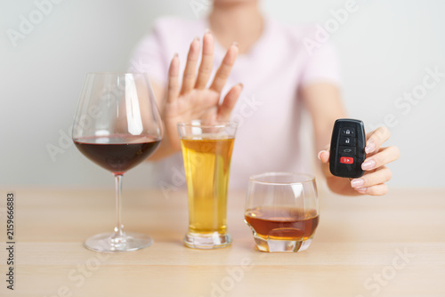 Bild auf Leinwand Responsible woman reject a drink before driving for road safety, stop hand gesture to refuse a glass of wine, beer, whiskey or cognac and car remote