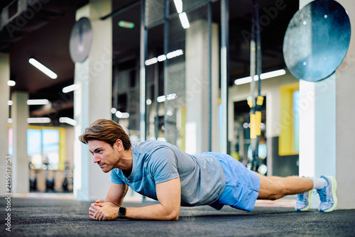 Obraz na plátně Man doing a plank exercise on gym floor, building core strength and endurance