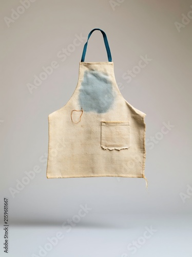 Repaired canvas work apron with a visible darning stitch and worn patina, featuring a neutral beige fabric and blue ties for a craft mockup