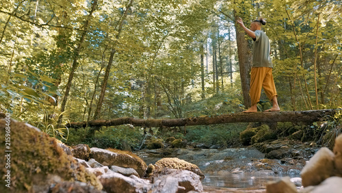 In a serene forest setting, a person practices yoga on a fallen log, balancing with focused grace. The tranquil environment and meditative pose highlight a commitment to a healthy lifestyle.