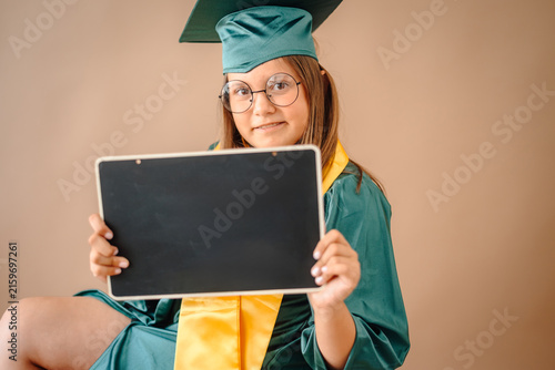 Obraz na płótnie School girl celebrating graduation holding blank board