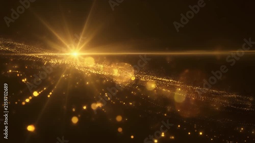 Golden particles flowing with a bright light source and lens flares.