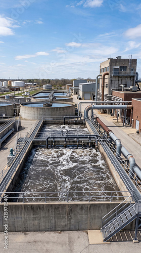 Industrial wastewater treatment plant with large concrete aeration tanks purifying liquid under blue sky