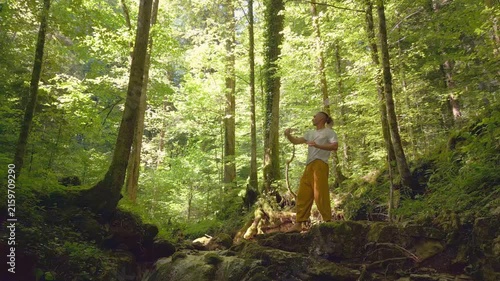 In a sun-dappled forest, a person practices yoga, balancing on one leg with arms outstretched. The serene environment enhances their meditative state, promoting relaxation and a healthy lifestyle.