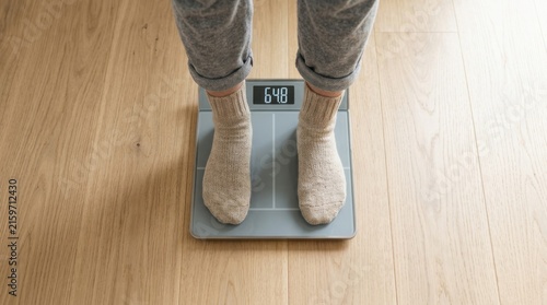 Person standing on digital weight scale in soft wool socks on hardwood floor monitoring body mass index for health and fitness goals in domestic