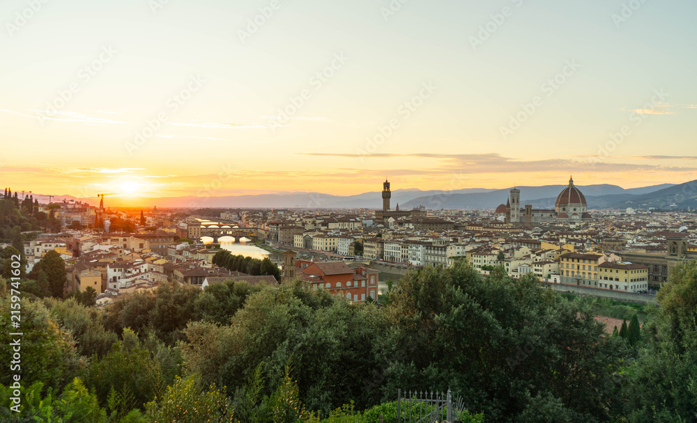 Fototapeta premium Vista panorámica de Florencia al atardecer con la catedral de Santa María del Fiore, el Ponte Vecchio y el río Arno desde un punto elevado.