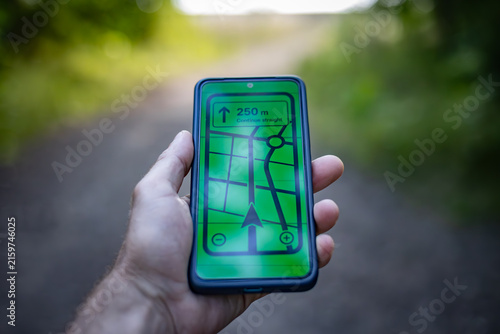 Cuadro en lienzo A man holds a smartphone with a GPS navigation app in nature.