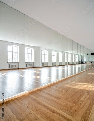 Empty dance studio with mirrors and wooden floor.