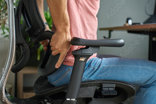Foto Man adjusting lumbar support on ergonomic office chair