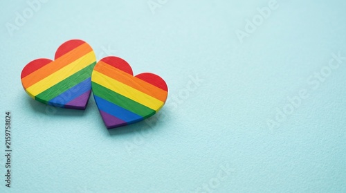 Rainbow pride hearts on blue background, LGBTQ love symbols for pride month, colorful heart shapes with copy space