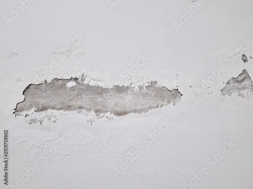 Peeling Plaster Texture: Close-up view of a damaged white wall with peeling plaster, revealing the underlying concrete and texture. A stark depiction of decay and neglect in building materials.