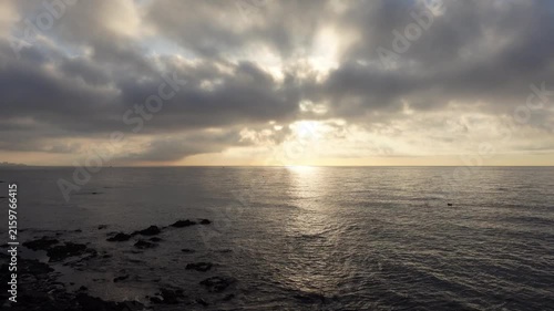 Time-lapse of stunning horizon line on the sea with sun between clouds at dawn or dusk. Sky and ocean waves moving fast
