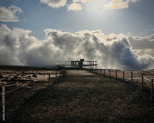 Iceland. Colorful geothermal landscape with steaming blue water and mineral-rich earth, showcasing a series of rocky formations and wooden walkways in a natural hot spring area