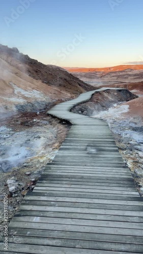 Iceland. Colorful geothermal landscape with steaming blue water and mineral-rich earth, showcasing a series of rocky formations and wooden walkways in a natural hot spring area