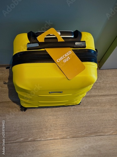 Reykjavik, Iceland - May 09, 2026: Yellow hard-shell suitcase with a checked-out tag attached, showcasing a modern design suitable for travel and luggage storage