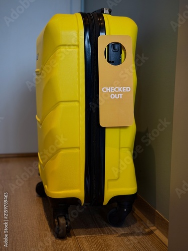 Reykjavik, Iceland - May 09, 2026: Yellow hard-shell suitcase with a checked-out tag attached, showcasing a modern design suitable for travel and luggage storage