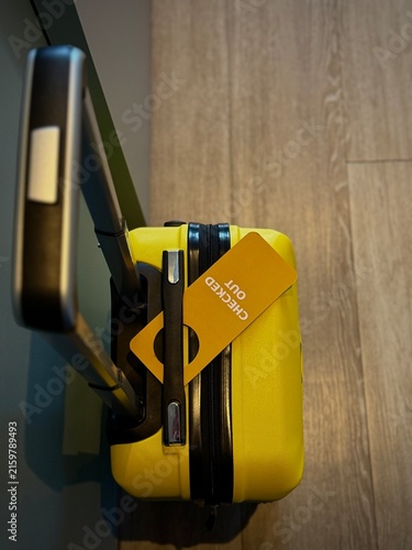 Reykjavik, Iceland - May 09, 2026: Yellow hard-shell suitcase with a checked-out tag attached, showcasing a modern design suitable for travel and luggage storage