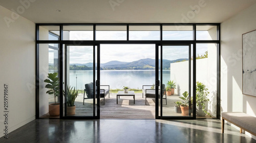 Modern Interior Opens to Serene Lake View with Outdoor Seating and Lush Plants