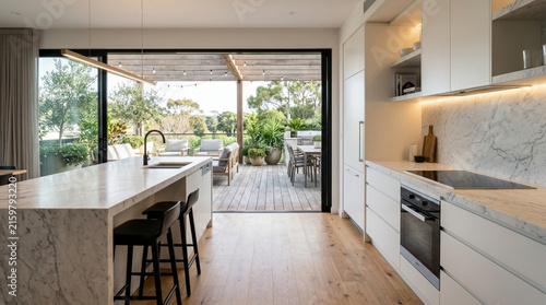 Modern Kitchen and Outdoor Patio with Island Bar, Marble Countertops, and Natural Light.