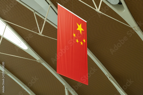 national flag of china hanging from ceiling of terminal. vertical flag with five stars symbolizing unity of country. concept of flag pride and state symbolism in modern public space