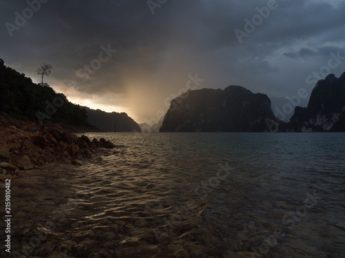 Ratchaprapha Dam in the morning featuring sunlight and mist amidst khao sok national park in surat thani province thailand where towering limestone cliffs rise from the freshwater reservoir.