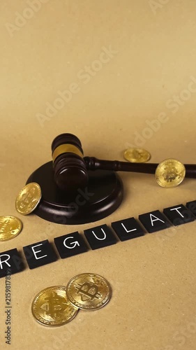 Golden bitcoins and a judge's gavel are positioned near black letter tiles spelling the word regulation, symbolizing the legal and financial rules governing digital currency transactions