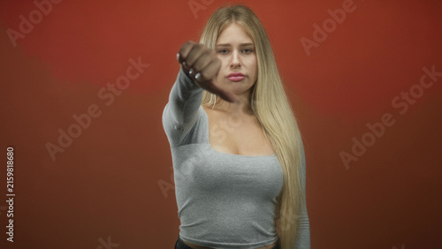 Photography Woman gives thumbs up with outstretched arm and visible thumb against red studio backdrop; approval