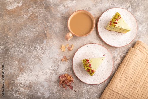 Pistachio green cake with cup of coffee on brown concrete, copy space, top view.