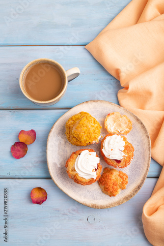 Сhoux pastry cake with cup of coffee on blue wooden, close up, top view.