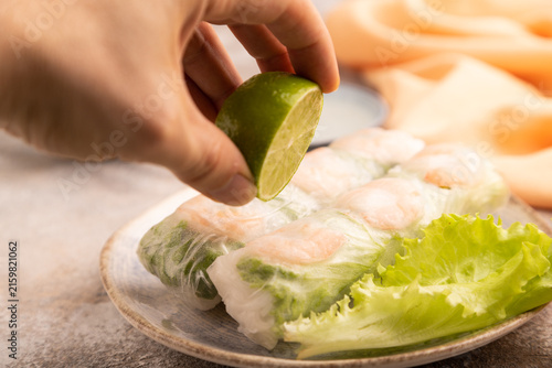 Vietnamese shrimp spring rolls with hand on brown concrete. side view, close up, selective focus